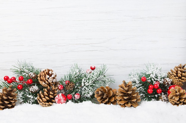 Cena de neve de natal galhos de árvores de natal com cones e ornamentos em fundo claro de madeira