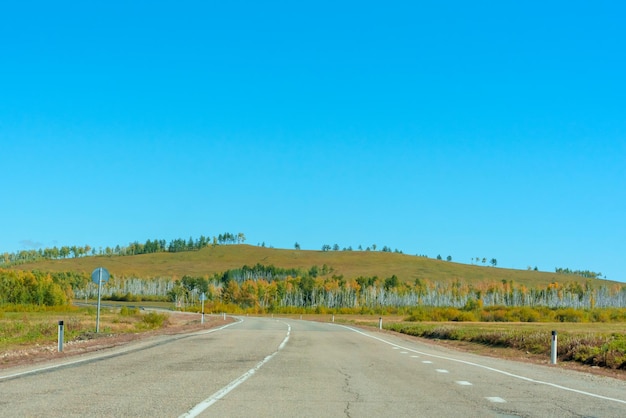 Cena de outono brilhante com estrada entre árvores laranja e verdes e céu azul Foco seletivo suave Beleza do conceito de viagem da natureza