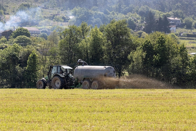Foto cena de um trator em um campo de colheita espalhando esterco líquido