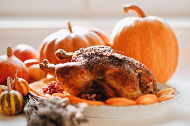 Cena del día de Acción de Gracias con decoración otoñal Delicioso pavo asado dorado en un plato adornado con rodajas de naranjas y calabazas de fondo blanco