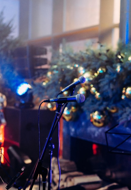 Foto cena do microfone no fundo de uma árvore de natal multicolorida e brilhante desfocando o bokeh da guirlanda