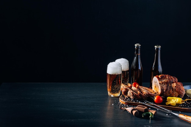 Foto cena para dos de carne y cerveza artesanal dos vasos de cerveza carne picada al horno con verduras en una bandeja de madera con tenedor de carne y especias