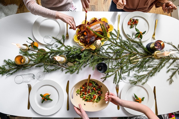 Cena festiva de navidad. Deliciosa comida tradicional de vacaciones y las manos de las personas que los comen. Mesa decorada con sabrosos platos. Ley plana. Mesa blanca