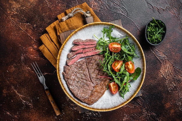 Cena con filetes de carne de ternera a la parrilla y ensalada de verduras. fondo oscuro Vista superior.