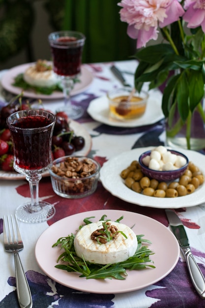 Foto cena gourmet camembert a la parrilla, vino blanco y varios aperitivos.