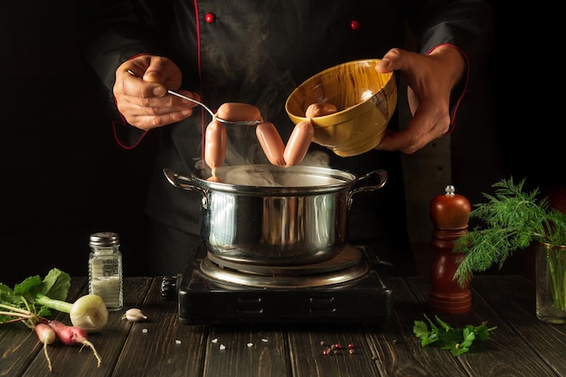 Para la cena hay que cocinar deliciosas salchichas de carne en una cacerola Chef en la cocina en el trabajo