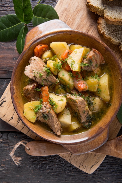 Cena irlandesa Carne de res guisada con papas, zanahorias y pan de soda en mesa de madera, vista superior, espacio de copia. Comida casera de invierno reconfortante - cocinada lentamente