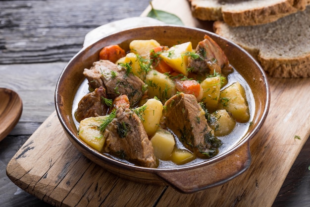 Foto cena irlandesa carne de res guisada con papas, zanahorias y pan de soda en mesa de madera, vista superior, espacio de copia. comida casera de invierno reconfortante - cocinada lentamente