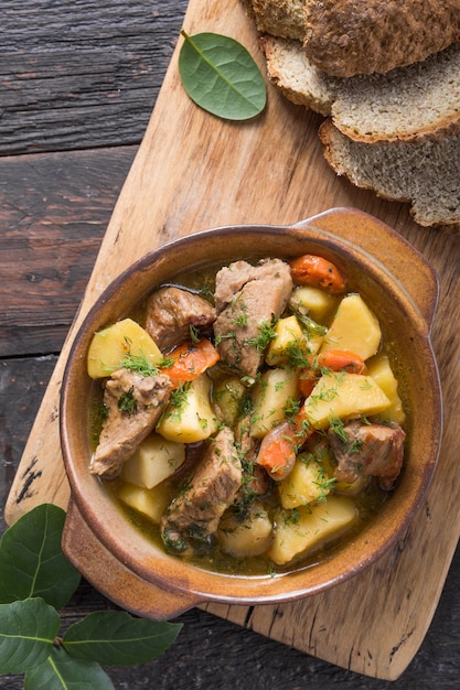 Cena irlandesa Carne de res guisada con papas, zanahorias y pan de soda en mesa de madera, vista superior, espacio de copia. Comida casera de invierno reconfortante - cocinada lentamente