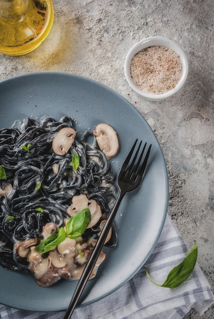 Cena italiana moderna Comida mediterránea Tinta negra de sepia pasta de espagueti con champiñones champiñones aceite de oliva y albahaca