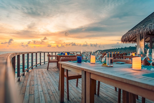 Cena de lujo al atardecer comida gourmet en mesa de madera, hermoso resort tropical y vista al mar, elegante