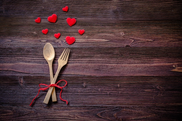 Cena con mesa en estilo rústico de madera con cubiertos, corazón rojo. Día de San Valentín.