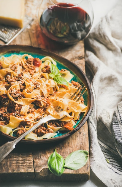 Cena de pasta con tallarines a la boloñesa y vino tinto en copa