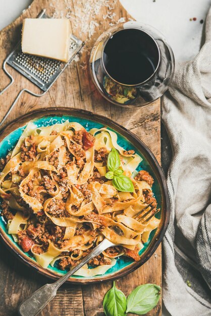 Cena de pasta con tallarines a la boloñesa y vista superior de vino tinto