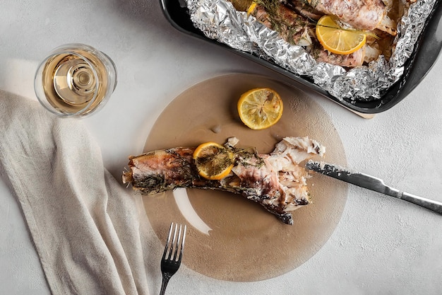 Cena de pescado al horno en papel de aluminio y una copa de vino blanco.