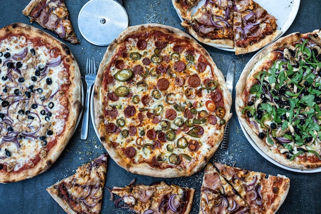 Cena de pizza Disposición plana de varios tipos de pizza italiana en la vista de mesa rústica Concepto de reunión de celebración de almuerzo rápido