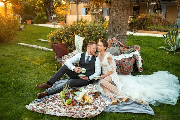 Cena de recién casados en el césped al atardecer.Una pareja se sienta y bebe té al atardecer en Francia