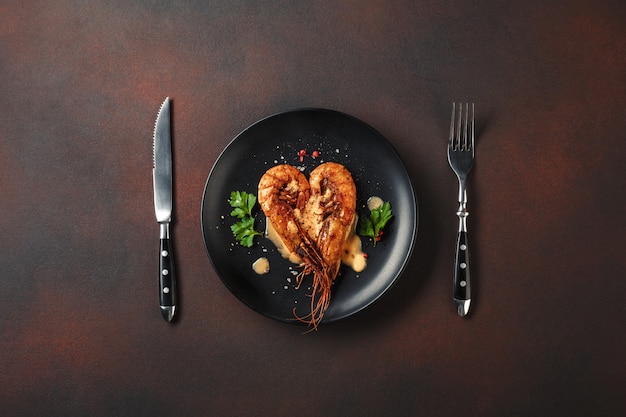 Cena romántica con camarones en forma de corazón y vino sobre un fondo marrón. vista superior con espacio de copia.