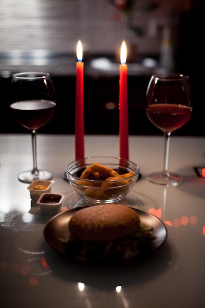 ¡Cena romántica, dos copas de vino y velas, hamburguesas, nuggets en la oscuridad con luces de año nuevo en el fondo!