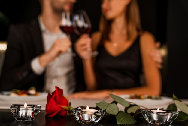 Cena romántica en la noche con enfoque en rosas y velas.