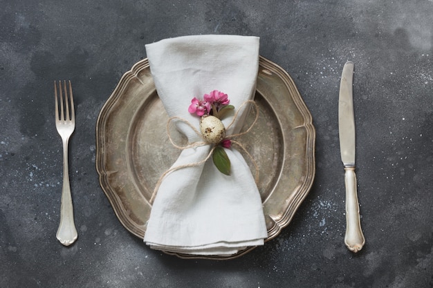 Cena romántica de Pascua. Ajuste de la tabla de la elegancia con las flores del rosa de la primavera en oscuridad. Vista superior.