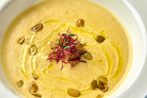 Cena saludable con souppuree de calabaza servida en un tazón blanco