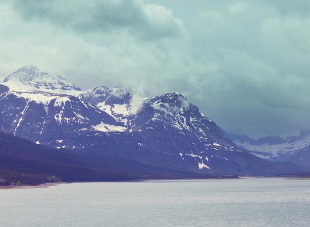 Cena serena à beira do lago de montanha no Canadá com o reflexo das rochas nas águas calmas.