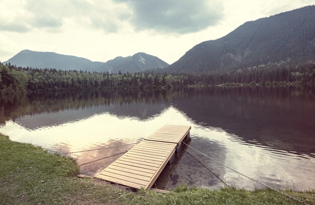 Cena serena à beira do lago de montanha no Canadá com reflexo das rochas nas águas calmas.