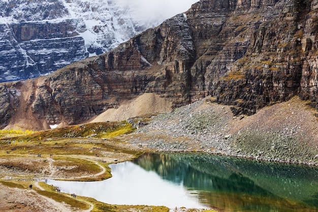 Cena serena à beira do lago de montanha no Canadá com reflexo das rochas nas águas calmas.
