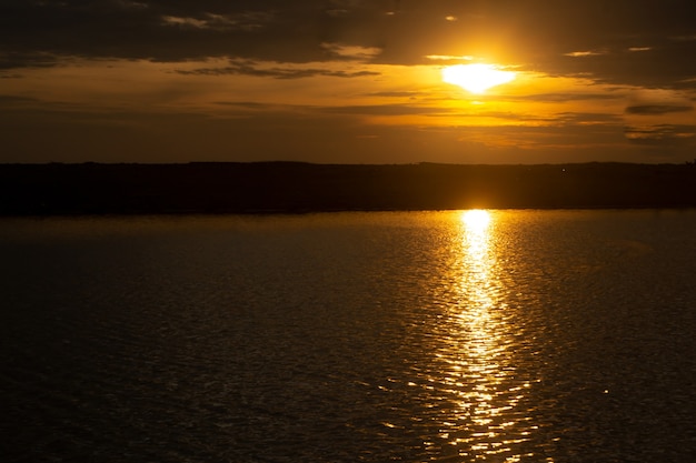 Cena tranquila do pôr do sol dourado na praia com nuvens