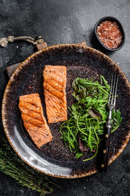 Cena vegetariana BBQ filetes de salmón a la parrilla en plato con ensalada Fondo negro Vista superior