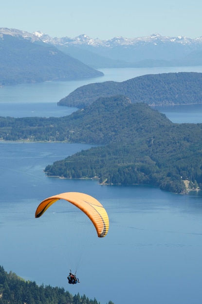 Cena vertical de parapente sobre lago e montanha