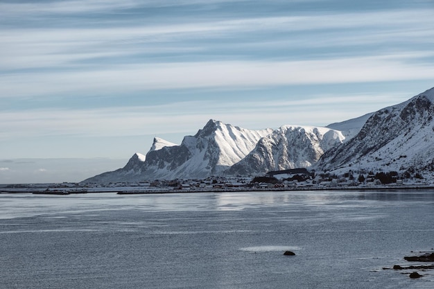 Cenário da cordilheira de neve com vila norueguesa no litoral