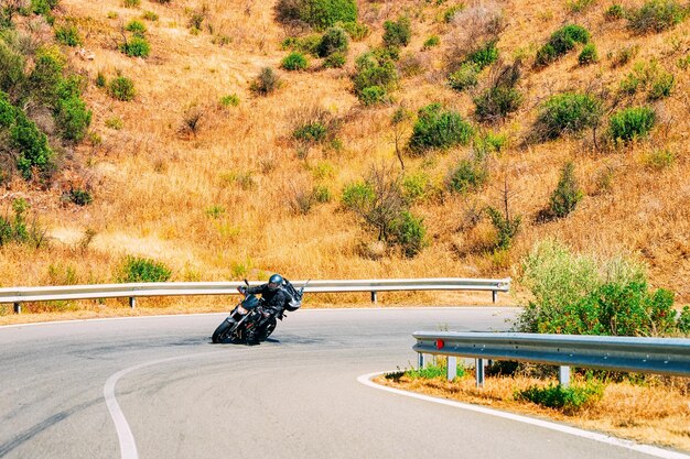 Cenário da motocicleta na estrada em Carbonia perto de Cagliari na Sardenha na Itália. Parte traseira da scooter e motociclista na estrada. Passeio de ciclomotor