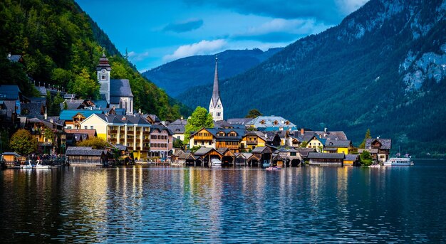 Cenário da noite da luz do sol de hallstatt no lago largo no fundo da floresta rochosa