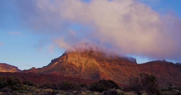 Cenário de lava na paisagem do deserto do Parque Nacional de Teide no pôr do sol Ilhas Canárias de Tenerife Nuvens coloridas montanhas laranja