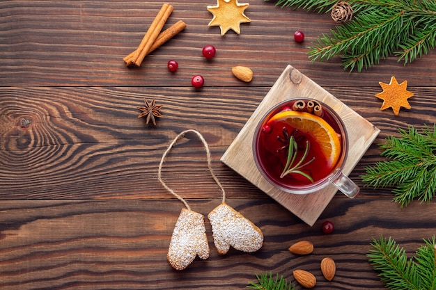 Cenário de madeira de Natal com ramos de abeto e especiarias aromáticas e biscoitos e uma xícara de chá