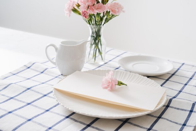 Cenário de mesa com pratos, talheres e flores em fundo branco