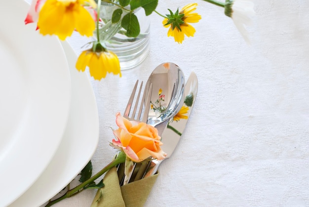 Cenário de mesa com pratos talheres e flores