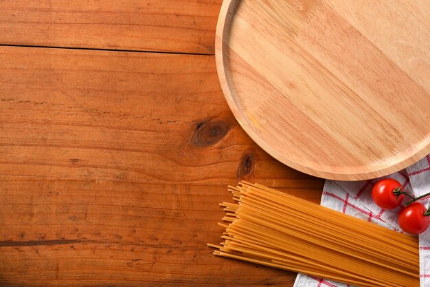 Cenário de mesa de jantar com placa de madeira de ingredientes de espaguete e espaço de cópia em fundo de madeira