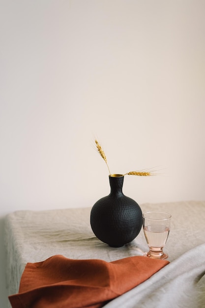 Cenário de mesa de jantar moderno Um lindo vaso preto com um guardanapo de linho sobre a mesa Apenas materiais naturais de barro, linho, flores secas