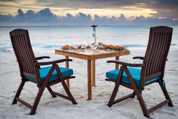 Cenário de mesa de jantar romântico na praia do pôr do sol