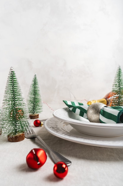 Cenário de mesa de Natal com pratos brancos, talheres, guardanapo e com uma decoração de Natal na toalha de linho com espaço de cópia. Inverno, tabela conceito festivo, servindo para o ano novo.