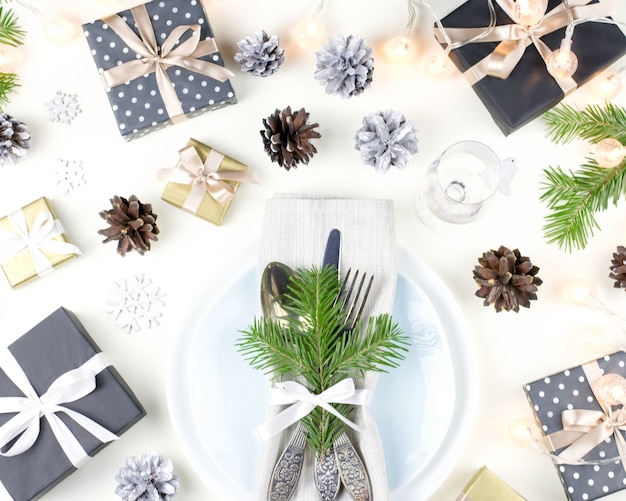 Cenário de mesa de Natal com pratos, talheres, presentes e enfeites. Vista do topo