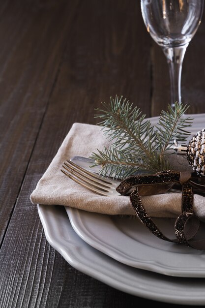 Cenário de mesa de natal com talheres e decoração perene natural escura.