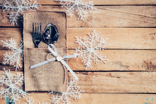 cenário de mesa de natal e talheres, flocos de neve em fundo de madeira com espaço.