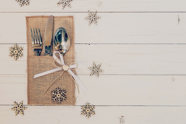 cenário de mesa de natal e talheres, flocos de neve na mesa de fundo de madeira com espaço para o natal.