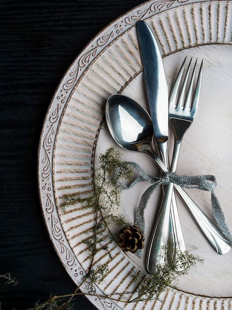 Cenário de mesa de natal vintage ou rústico Talheres de prato branco elegante e galho de pinheiro natural na superfície de madeira