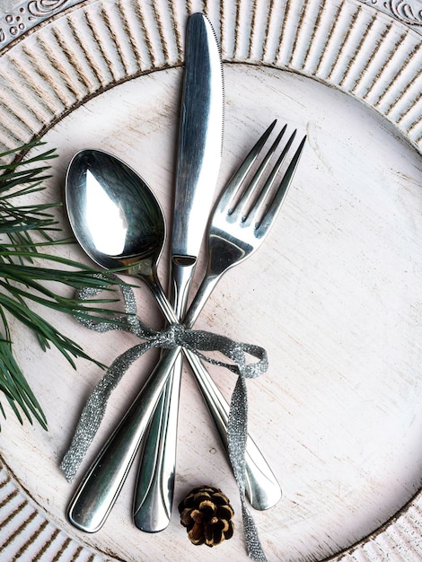 Cenário de mesa de natal vintage ou rústico Talheres de prato branco elegante e galho de pinheiro natural na superfície de madeira