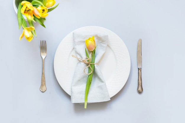 Cenário de mesa de Páscoa com tulipa amarela em azul pastel.